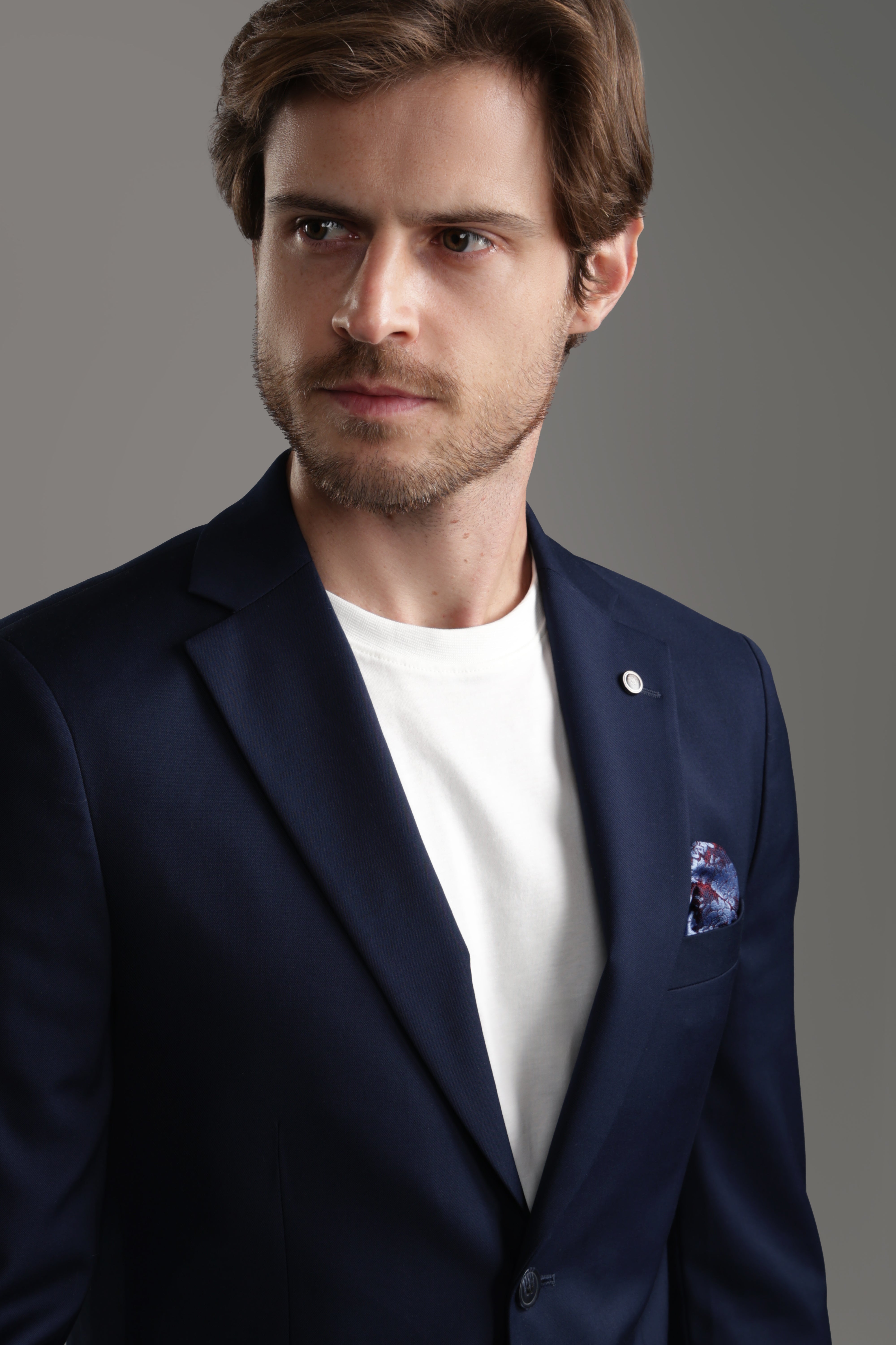 Man wearing a sophisticated navy suit jacket with a pocket square, featuring a polished look for formal occasions.