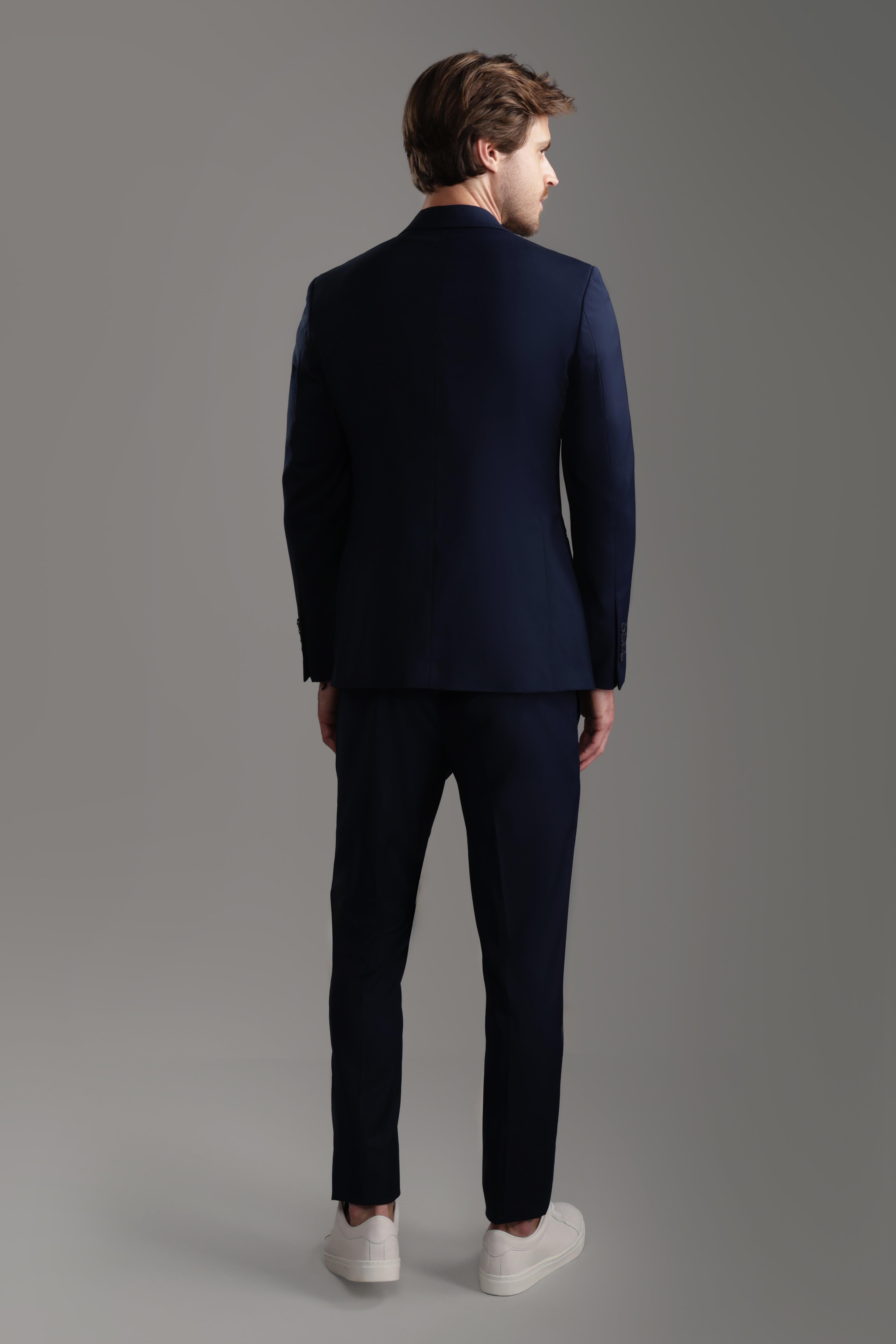 Back view of a sophisticated navy suit featuring tailored pants and a classic jacket, perfect for formal occasions.