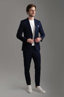 Man in a tailored navy suit with a white t-shirt and sneakers, showcasing a modern formal look.