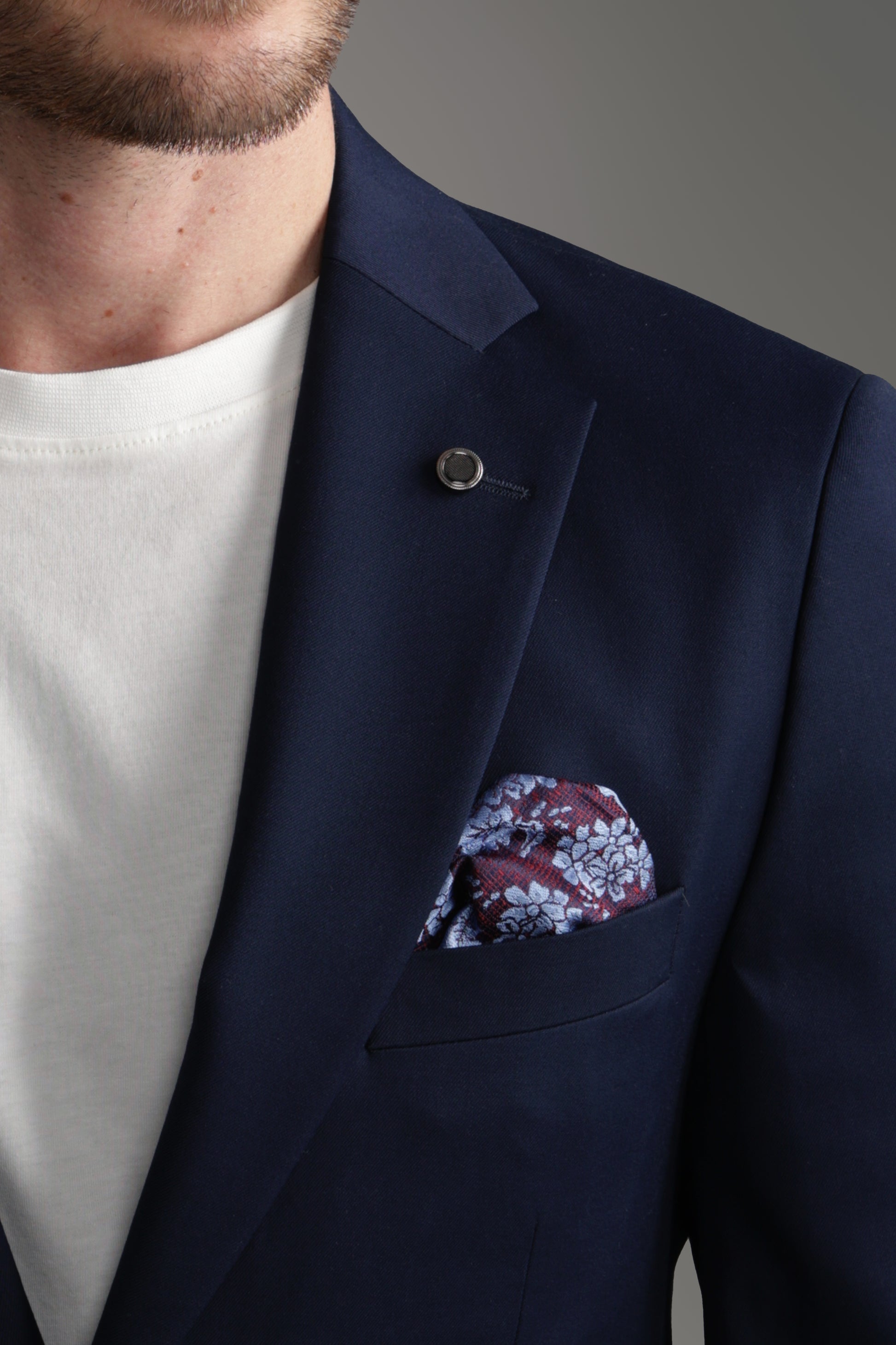 Close-up of a man in a navy suit jacket with a floral pocket square, elevating formal style.